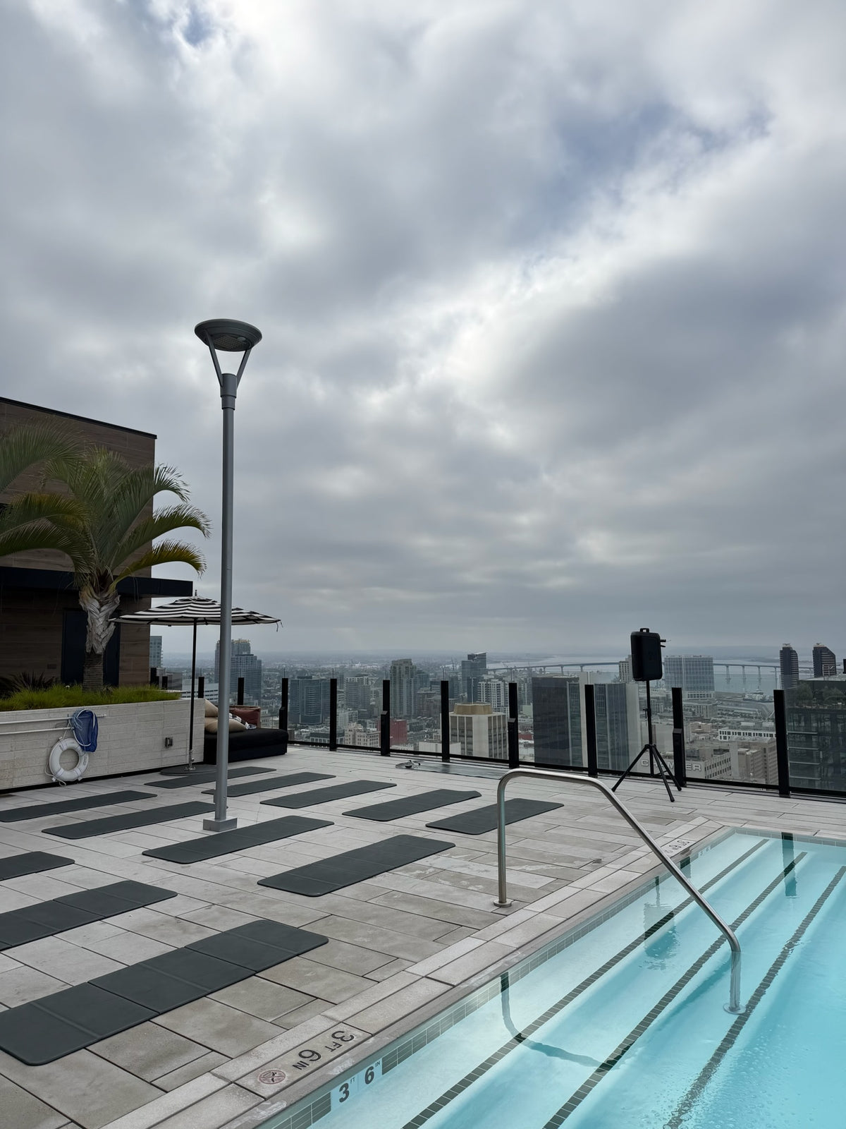 Poolside Club Sweat setup at a luxury residence: mats and sculpt balls laid out on the lawn beside the pool