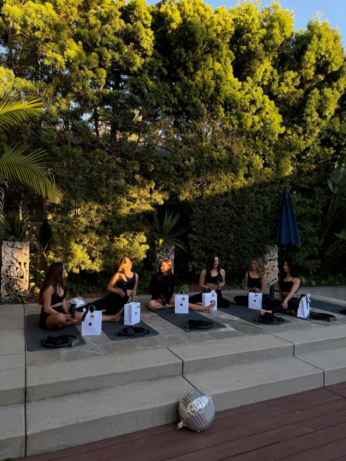 Sculpt class with Pilates rings on mats under palm trees at a Club Sweat event
