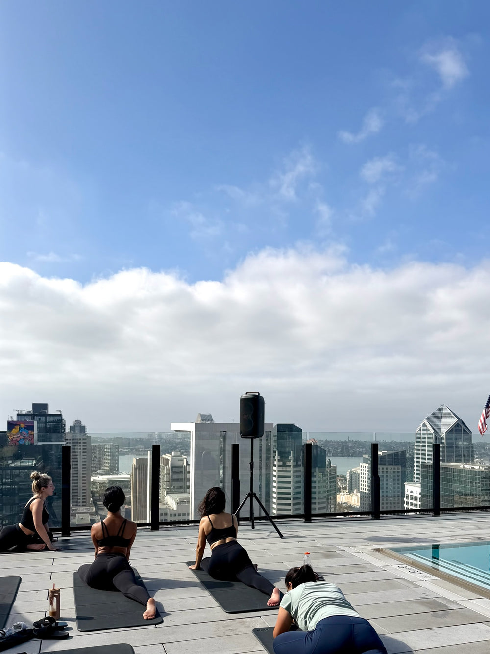 Residents in a rooftop Club Sweat class, kneeling on mats with Pilates balls