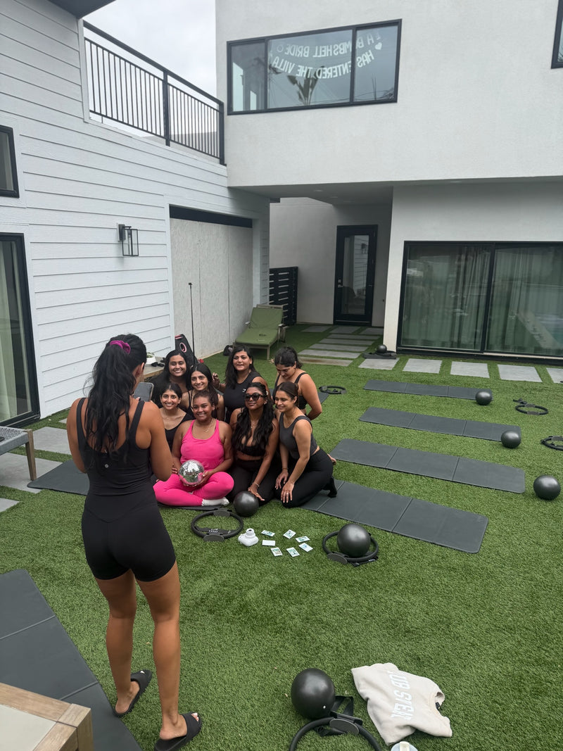 Bachelorette group posing with a disco ball on mats in a San Diego backyard after a private Club Sweat sculpt class