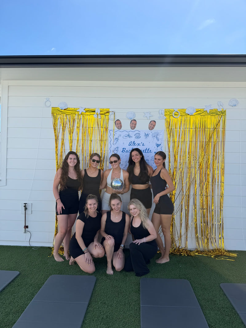 Bachelorette group posing with a disco ball in front of a gold fringe backdrop at a Tampa Club Sweat workout