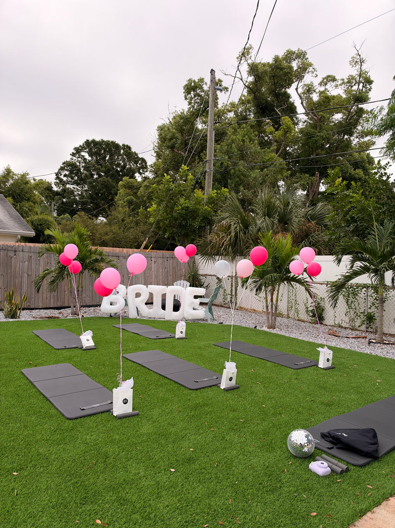 BRIDE balloons and workout mats set up on a Tampa backyard lawn for a Club Sweat bachelorette session